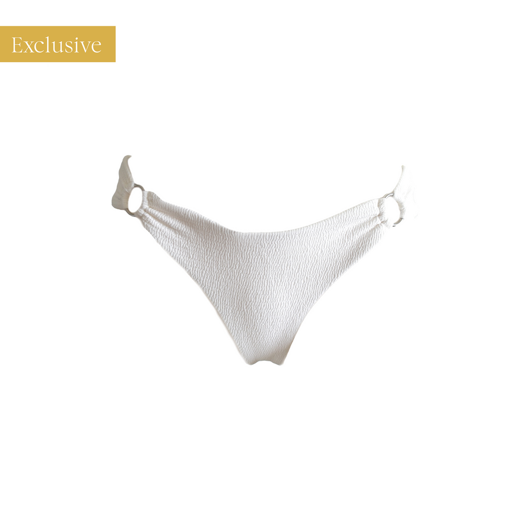 Luxe, wit bikini broekje uit onze exclusieve 'Goddess collection'. Dit witte bikini broekje is dubbel gevoerd, naadloos en duurzaam. Het bikini broekje is gemaakt van een dikke, luxe crinkle stof. Aan de binnenkant is het broekje gevoerd met onze zachte ECONYL® stof. Een duurzaam bikini broekje dat meerdere seizoenen mooi blijft. Wit Brazilian bikini broekje met zilveren ringen.